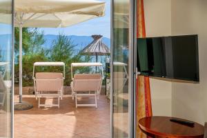 a patio with chairs and a television and a table at Hotel Dobrovit ex Tamaris in Baška