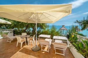 a patio with a table and chairs and an umbrella at Hotel Dobrovit in Baška