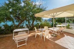 a patio with a table and chairs and an umbrella at Hotel Dobrovit in Baška