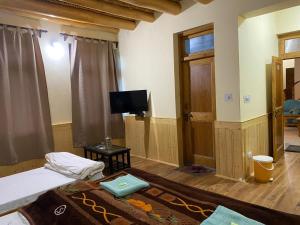 a room with a bed and a flat screen tv at Zaltak Guest House and Hostel in Leh