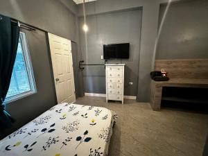um quarto com uma cama, uma televisão e uma janela em Limewood Residences- Bago City near Bacolod em Bago