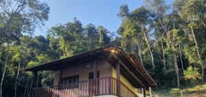 a small house with a balcony in front of a forest at Chalé Céu de Minas in Visconde De Maua