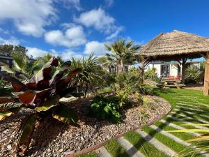 a garden with a thatch hut and a bench at Camping de la côte des légendes in Brignogan-Plages