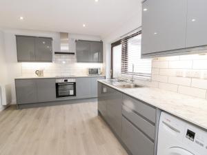 a large kitchen with stainless steel appliances and gray cabinets at Cae Teg in Llanfairpwllgwyngyll