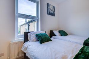 Duas camas com almofadas verdes num quarto com uma janela em Peckham Plaza em Londres