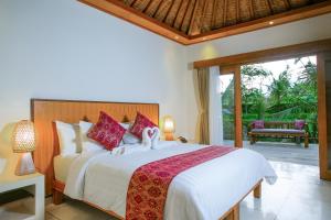 een slaapkamer met een groot bed en een patio bij Pesantian Villa and Warung in Ubud