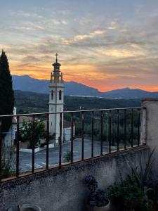 a building with a clock tower with a sunset in the background at El Mirador de Benialfaqui, apartamento Els Olivers 