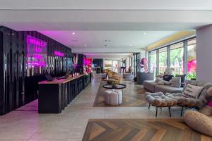 a lobby with couches and a bar with pink lights at Housi Boutique Faria Lima By Belong in Sao Paulo