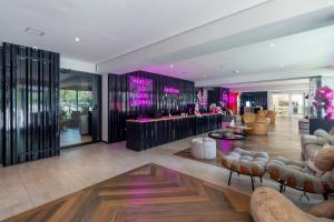 a lobby with a bar with pink lights on the wall at Housi Boutique Faria Lima By Belong in Sao Paulo