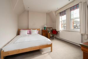 1 dormitorio con 1 cama, escritorio y ventanas en JOIVY Elegant house with patio in Fulham, en Londres