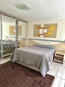 1 dormitorio con cama y espejo grande en Saint Sebastian Flat 206 - Com Hidro! até 4 pessoas, Duplex, no centro en Jaraguá do Sul