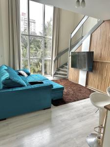 a bedroom with a blue bed and a tv at Saint Sebastian Flat 206 - Com Hidro! até 4 pessoas, Duplex, no centro in Jaraguá do Sul