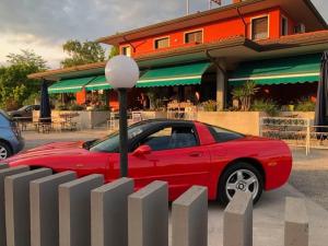 a red car parked next to a fence at Locanda Rossa in Romans di Varmo