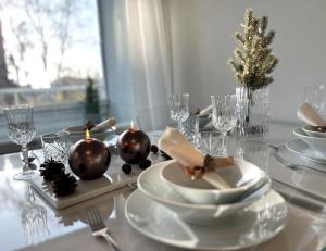 una mesa con platos blancos y adornos navideños en ella en Arctic Luxury Apartment, en Rovaniemi 9 fotos más