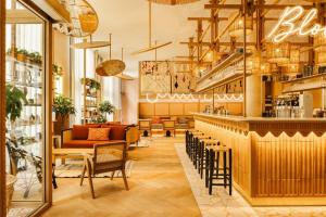 un restaurante con un bar con mesas y sillas en Bloom House Hôtel & SPA en París