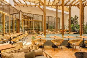 a restaurant with tables and chairs and a pool at Bloom House Hôtel & SPA in Paris