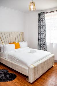 a bedroom with a large white bed with a couch at Kathy's Two Bedrooms in Nairobi