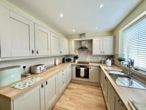 a large kitchen with white cabinets and a sink at Pass the Keys Pembroke Dock Hidden Gem in Pembroke Dock