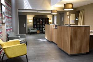 a waiting area of a library with yellow chairs and tables at Timhotel Opera Madeleine in Paris