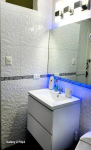 La salle de bains est pourvue d'un lavabo blanc et d'un miroir. dans l'établissement Mini Departamento Acogedor, à La Molina