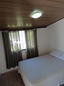 a bedroom with a white bed and a window at sítio recanto verde do sol in Guarapari