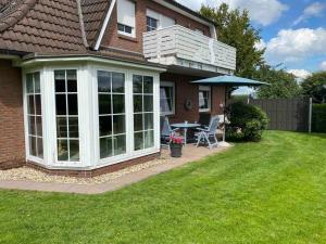 a house with a patio with a table and an umbrella at Ferienwohnung Sommer in Bramstedt