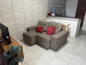 ein Sofa mit zwei roten Kissen im Wohnzimmer in der Unterkunft Casa Praia de Gaibu in Cabo de Santo Agostinho