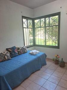 a bedroom with a bed with blue sheets and two windows at Rincón Verde Chacras de Coria in Ciudad Lujan de Cuyo