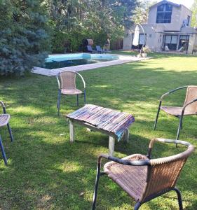 a group of chairs and a table in the grass at Rincón Verde Chacras de Coria in Ciudad Lujan de Cuyo