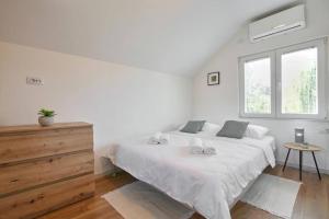 ein weißes Schlafzimmer mit einem großen Bett und einem Fenster in der Unterkunft Kuca za odmor Villavera in Donja Lomnica