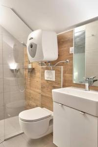 a white bathroom with a toilet and a sink at Kuca za odmor Villavera in Donja Lomnica