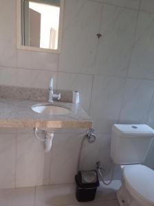 een witte badkamer met een wastafel en een toilet bij sítio recanto verde do sol in Guarapari