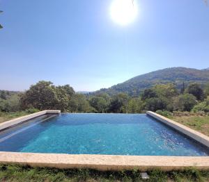 une grande piscine d'eau avec une montagne en arrière-plan dans l'établissement Domaine de la Cascade Parfumée, à Grasse