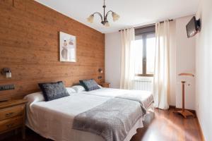 1 dormitorio con 1 cama y pared de madera en Hotel Rural Rio Viejo en Cubillas de Arbas