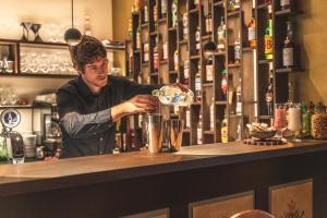 a bartender making a drink at a bar at Schwarzer Adler in Siusi