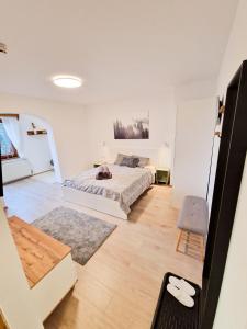 ein weißes Schlafzimmer mit einem Bett und einem Stuhl in der Unterkunft LOBE Apartment in Bad Mitterndorf
