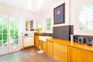 una cucina con pareti bianche, armadi in legno e finestre di Grand & Classy Apartment with Private Garden, Villa des Ammonites a Meudon