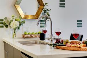 a kitchen with a sink and two glasses of wine at Coastal Creative Condo in Victoria