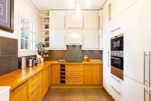 a kitchen with wooden counters and white cabinets at Grand & Classy Apartment with Private Garden, Villa des Ammonites in Meudon