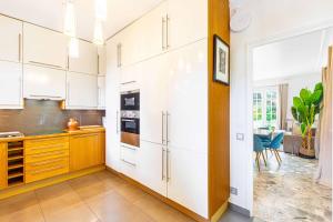 a kitchen with white cabinets and a large window at Grand & Classy Apartment with Private Garden, Villa des Ammonites in Meudon