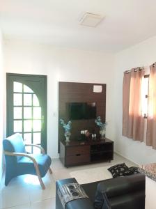 uma sala de estar com uma televisão e uma cadeira azul em sítio recanto verde do sol em Guarapari