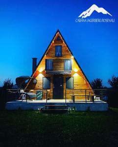 uma casa de madeira com luz à noite em Cabana JagerBerg Rosenau em Rasnov