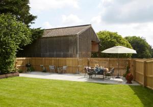 a patio with a table and an umbrella in a yard at The Old Barn at Moor Farm in Godshill