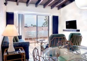 uma sala de estar com uma mesa de vidro e cadeiras em WIVC La Paloma Resort - Your Vacation Escape to Rosarito, Swimming Pool & Short Walk To The Beach em Popotla