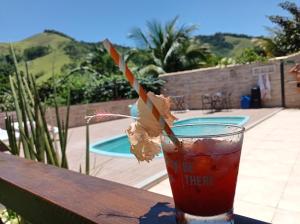 a drink sitting on a table next to a pool at sítio recanto verde do sol in Guarapari