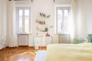 a white bedroom with two beds and two windows at Vicolo Parchetto 9 in Ferrara