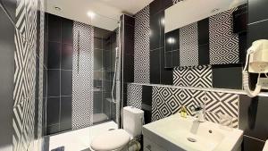 a bathroom with black and white tiled walls and a sink at Hotel Le Florian in Cannes