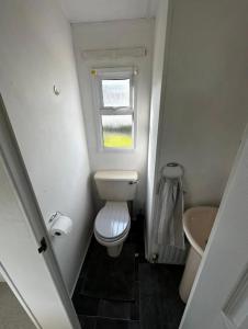 a small bathroom with a toilet and a window at 2 Bedroom Caravan With Sea Views in Eastchurch