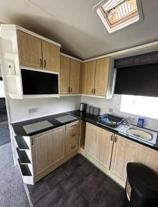 a small kitchen with wooden cabinets and a sink at 2 Bedroom Caravan With Sea Views in Eastchurch