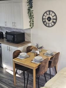 a dining room table with chairs and a clock on the wall at Serviced Apartment - Aberdeen in Dyce